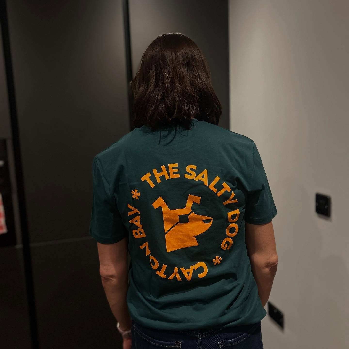 Forest green Salty Dog tee with orange logo modelled from the back