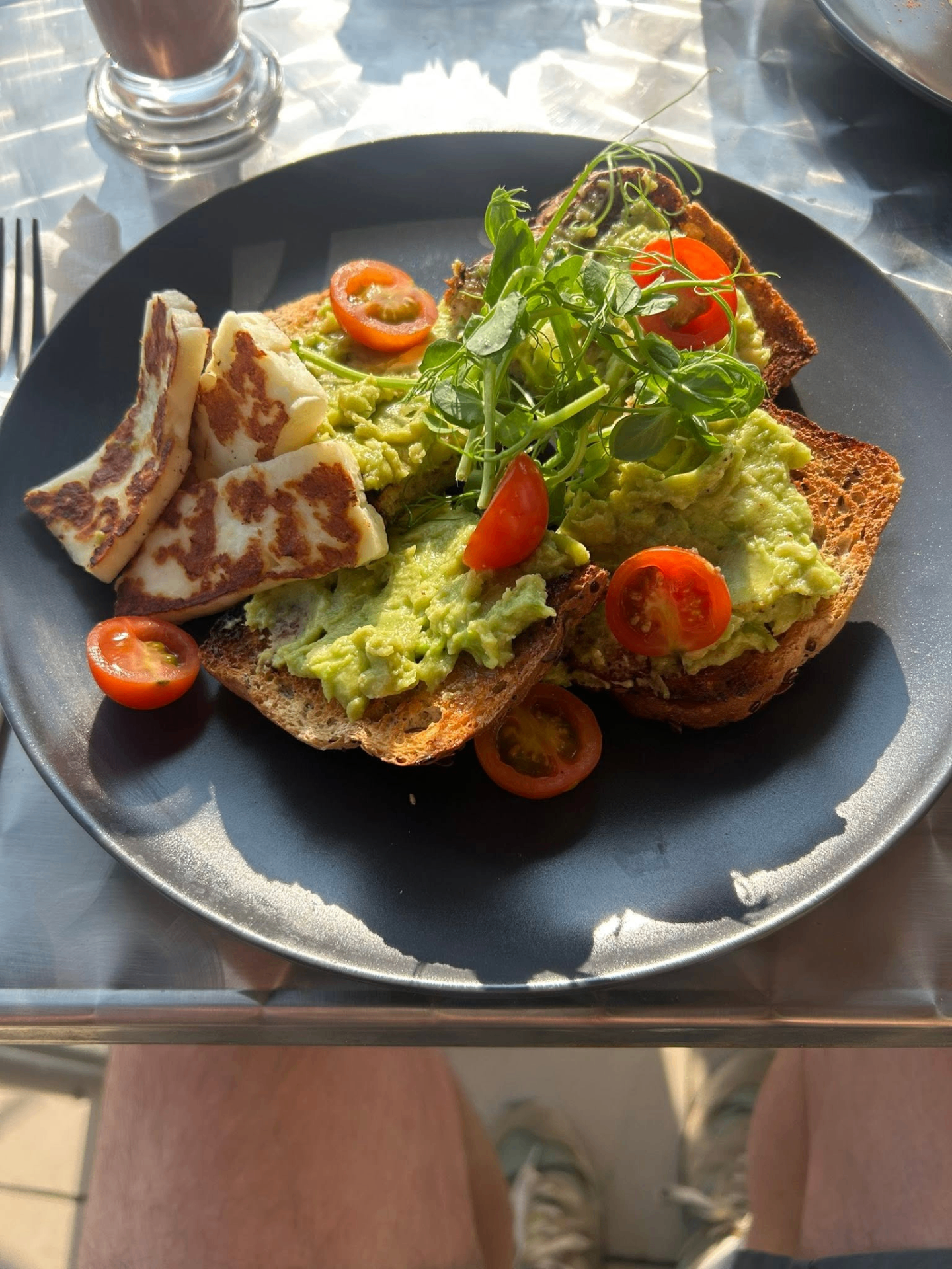 Avocado toast with cherry tomatoes and grilled halloumi on a dark plate