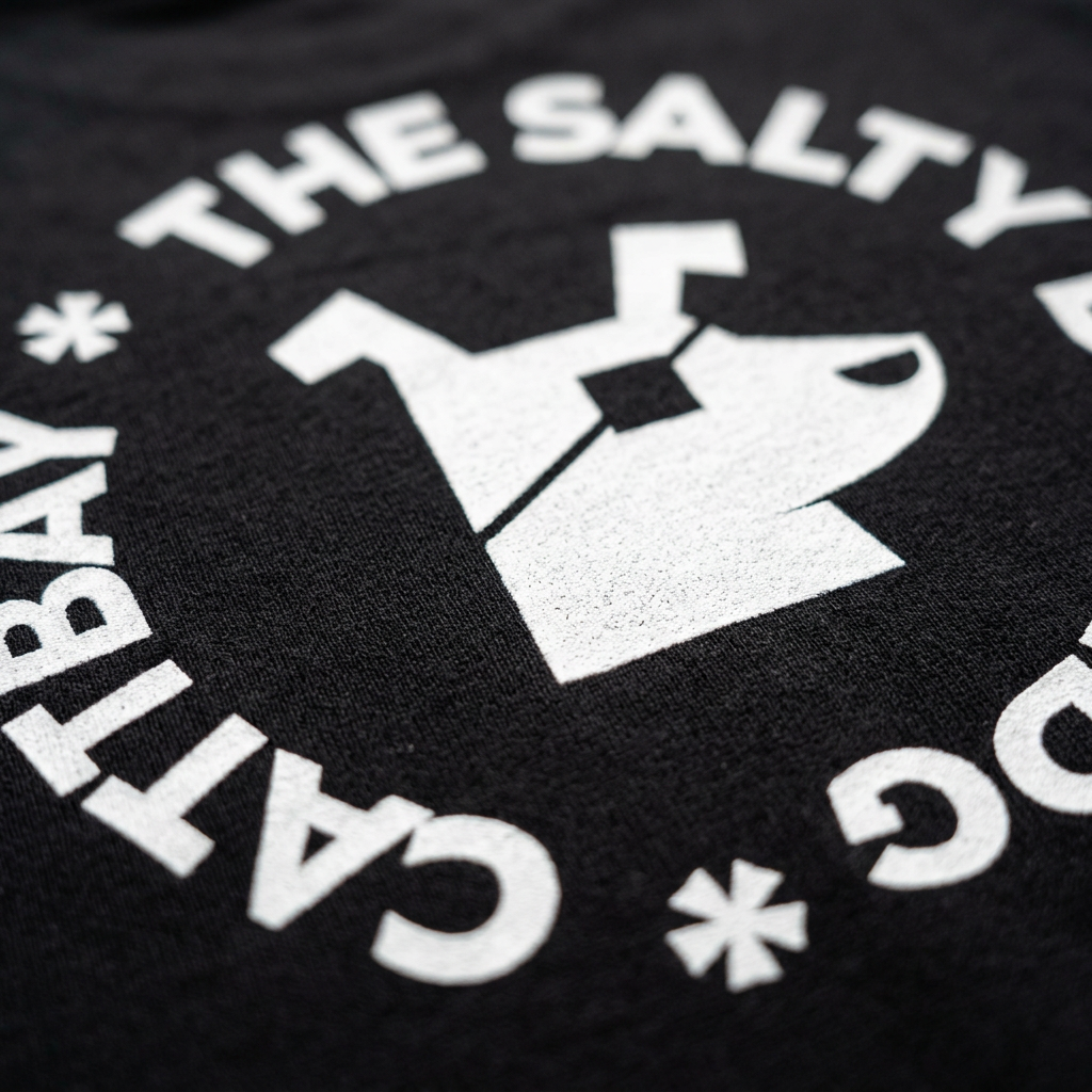 Close-up of the white circular dog logo printed on black cotton